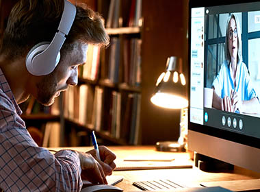 male-student-wearing-headphones-conference-video-calling-watching-webinar-online-training-class-virtual-chat-meeting-with-remote-teacher-or-coach-distance-learning-using-computer-taking-notes